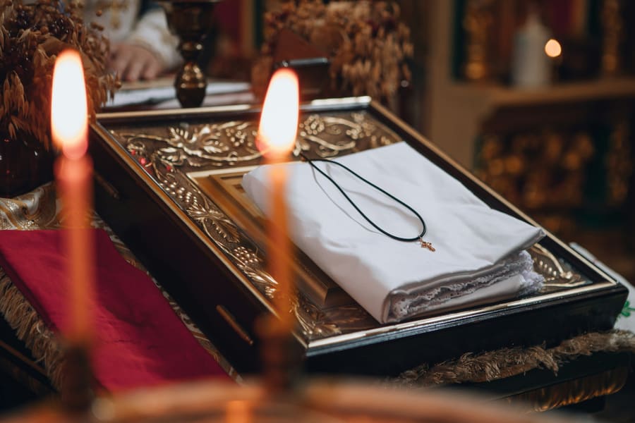 A white christening cloth and a small cross on an ornate tray.