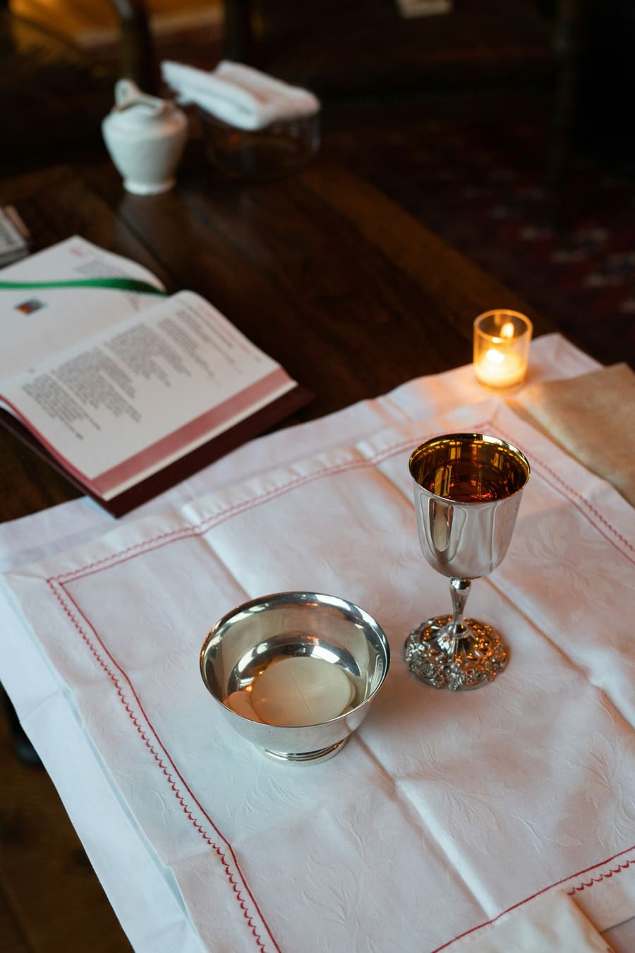 A silver chalice and paten on a white linen cloth.